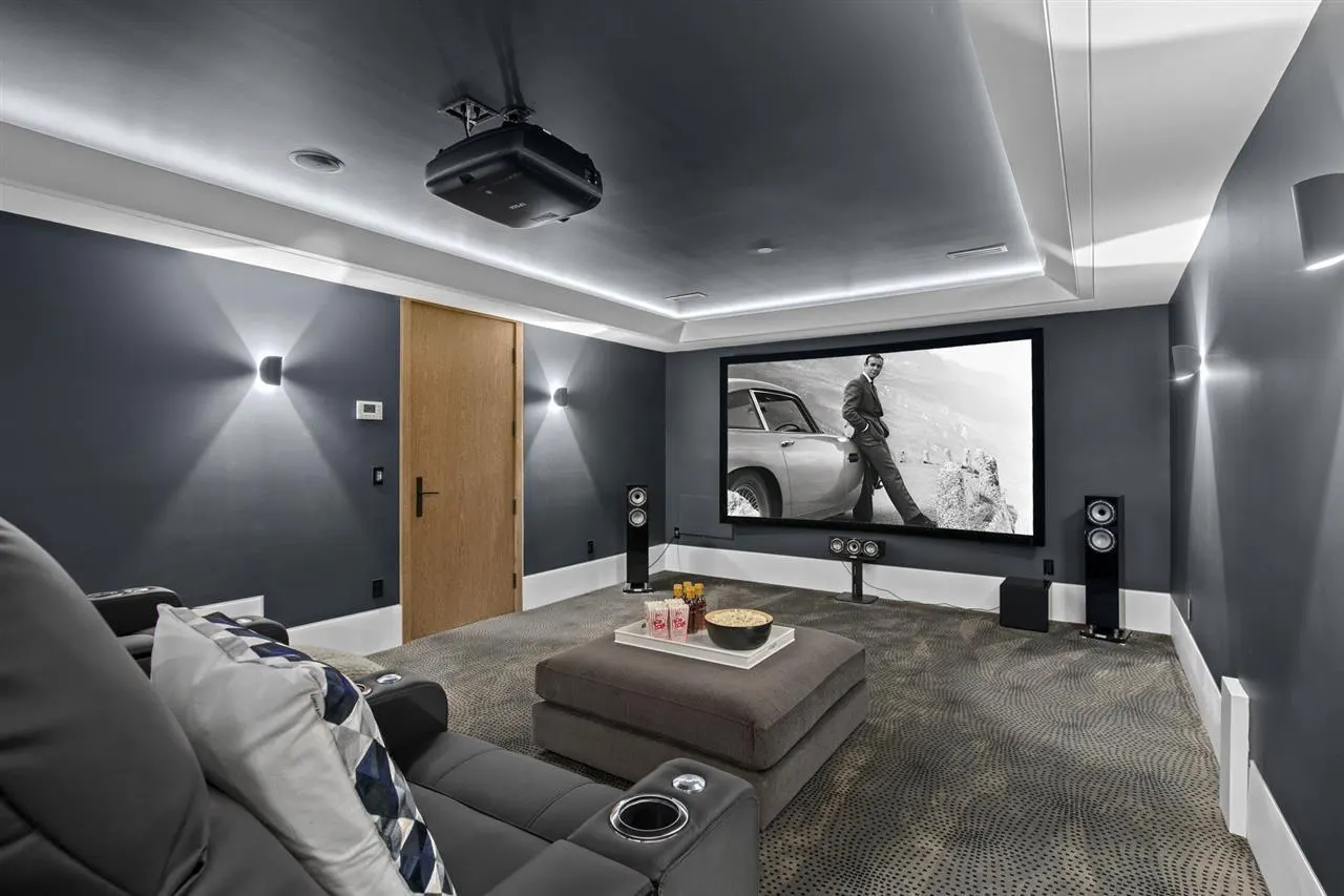 Dedicated home theatre with a ceiling projector, in-ceiling speakers, and a theatre recliner.