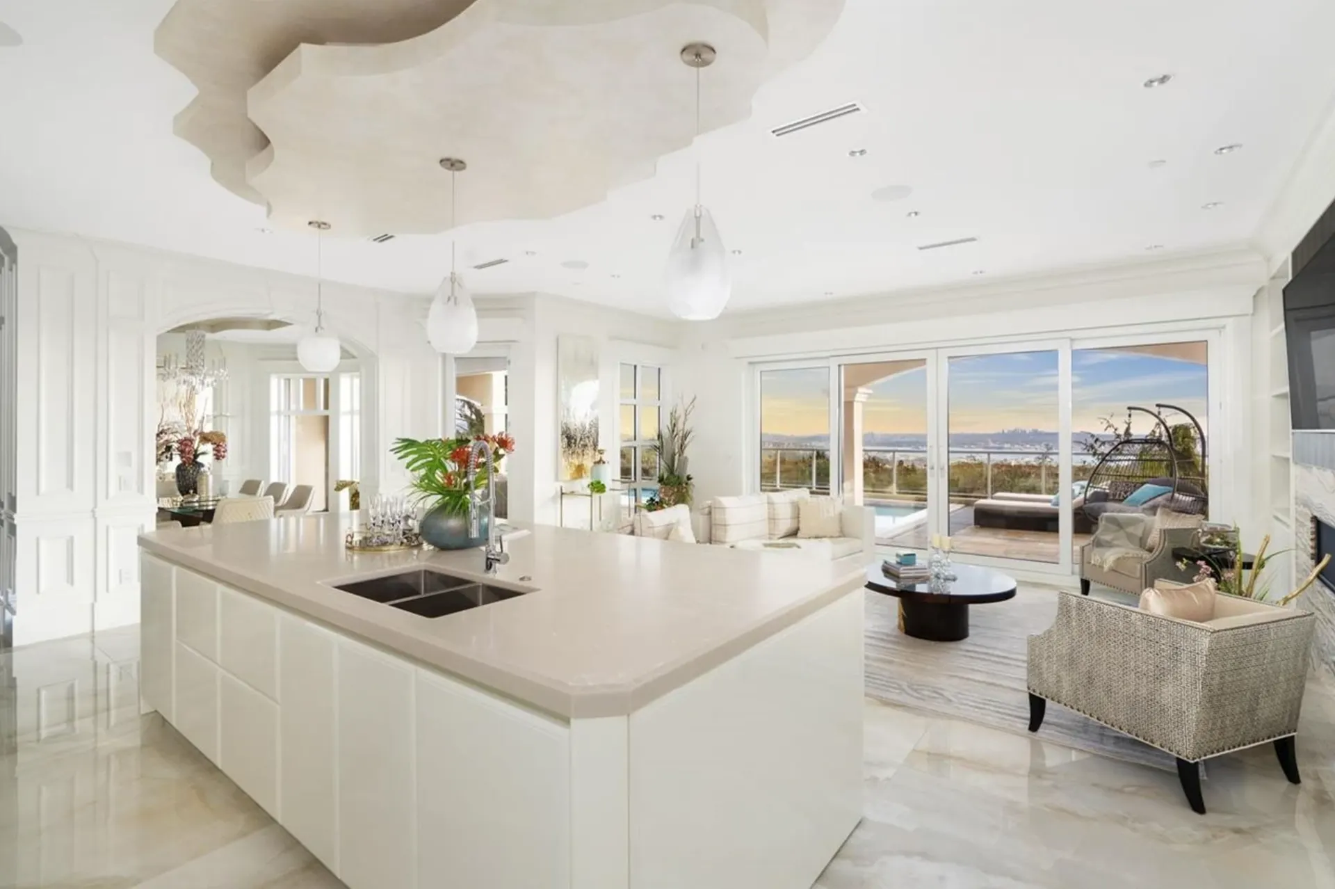 Open kitchen and living room with in-ceiling speakers, recessed lighting, and a wall-mounted TV.
